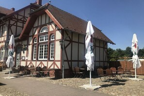 Ein traditionelles Fachwerkhäuschen mit Außenbestuhlung und Sonnenschirmen.