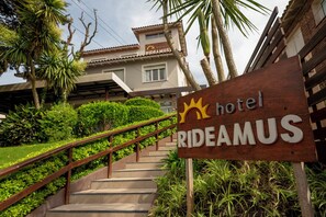 Un letrero de madera del hotel 'RIDEAMUS' con una escalera que conduce al edificio.