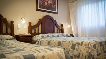 A hotel room with two beds, a nightstand with a telephone, wall-mounted lamps, and a painting on the wall.
