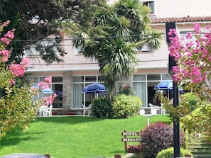 Un hotel con un letrero que dice 'HOTEL RIDEAMU', rodeado de exuberante vegetación y plantas en flor.