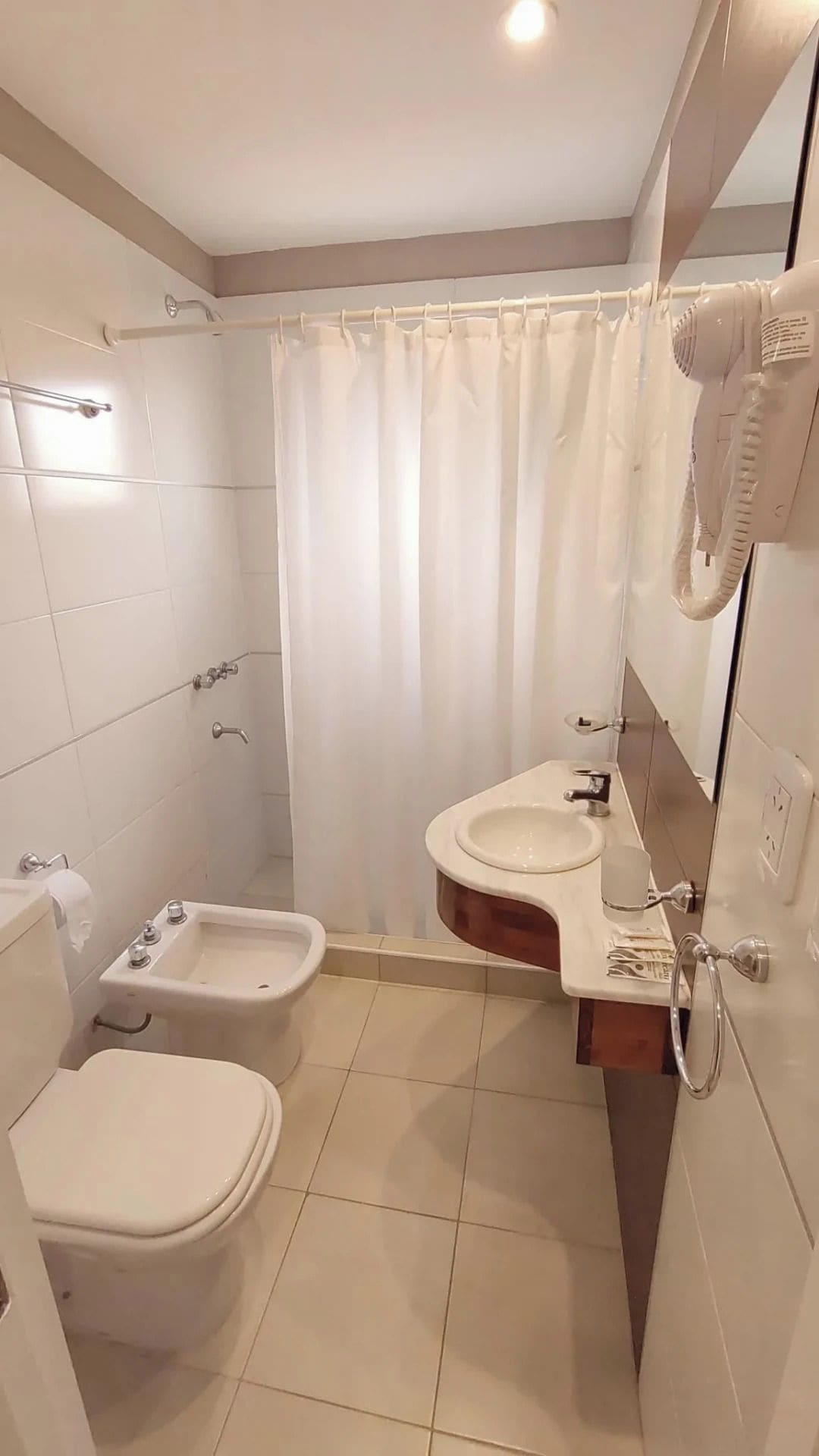 Een badkamer met toilet, wastafel en bidet.