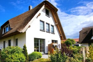 A modern house with a steeply pitched roof, large windows, and a well-maintained garden. - Holiday apartment Bug (Dranske)