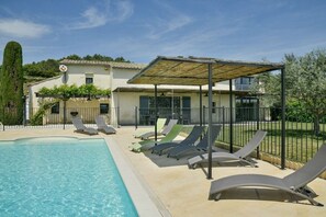 Une piscine avec des chaises longues et un espace de détente abrité.