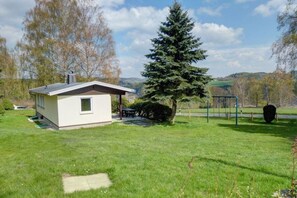 A small, single-story building with a sloped roof, a covered patio area, and a well-maintained lawn. - Holiday home with 1 bedroom (Marienberg\/OT Rittersberg)