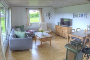A living room with a sofa, a table, a TV, and a window. - Holiday home with 1 bedroom (Marienberg\/OT Rittersberg)