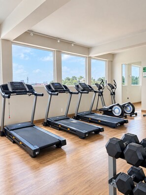 Ein Fitnessraum mit Laufbändern, Crosstrainern und Kurzhanteln.