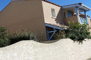 A building with a flat roof, a balcony with a blue railing, and a small window with a metal grill. - Holiday home in Gruissan with swimming pool (Gruissan)