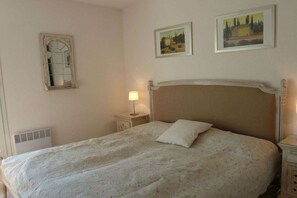 A bedroom with a bed, a nightstand, a lamp, a mirror, and two framed pictures on the wall. - Holiday home in Gruissan with swimming pool (Gruissan)