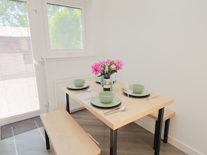 A dining table with green plates, a vase with pink flowers, and a bottle of wine. - Mullingarroch Mill — Historic Mill House on the River Spey, Sleeps 6 (Boat of Garten)