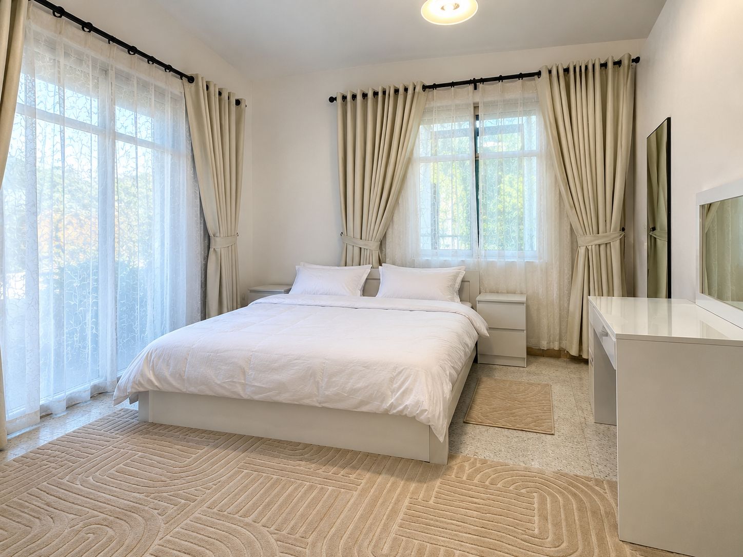 A bedroom with a bed, bedside tables, a dresser, and curtains.