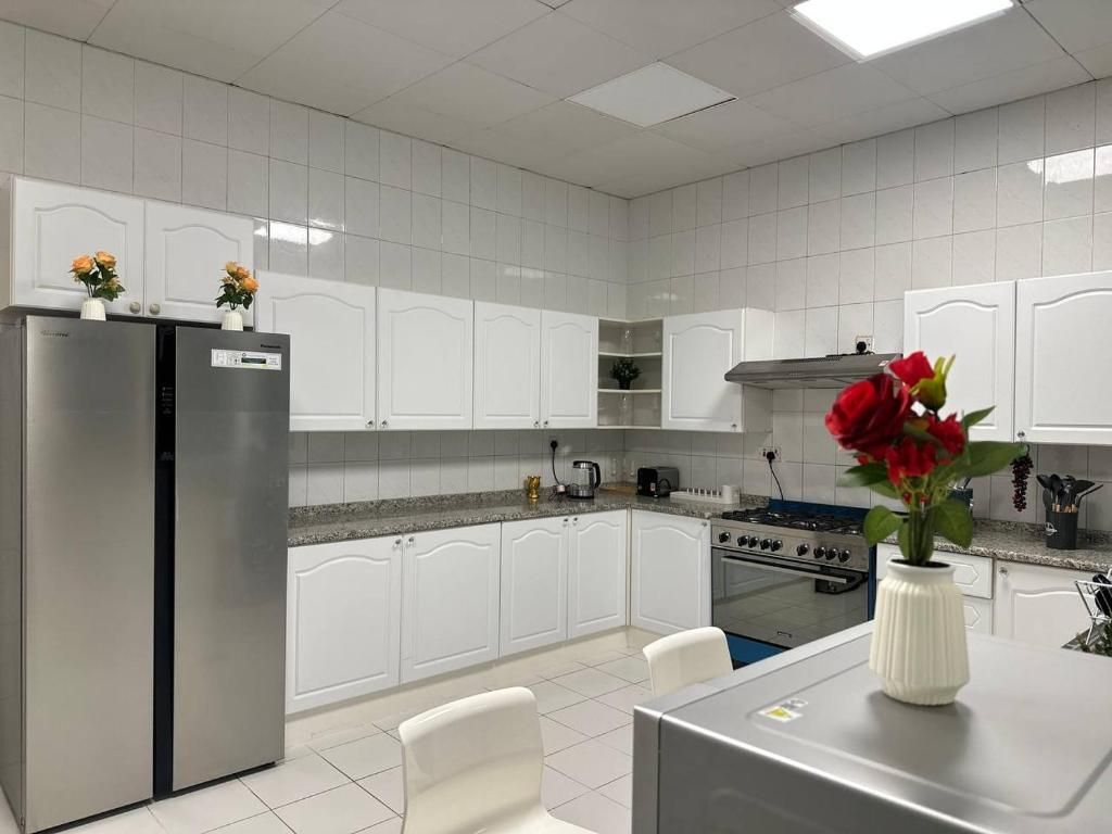 Una cocina moderna con muebles blancos, electrodomésticos de acero inoxidable y una isla central con un jarrón de flores.
