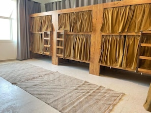 A bunk bed with a ladder, a patterned rug, and curtains.