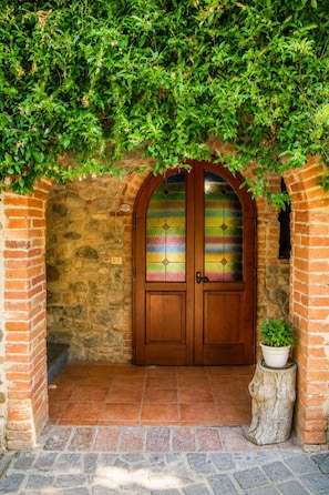 A stone archway leading to a wooden door with stained glass panels. - Cetine Vecchie Farmstay – The Winery (Torrita di Siena)