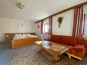 A room with a bed, a sofa, a table, and a hanging plant. - Vacation rental with a kitchen-living room and a separate bedroom, accommodating up to 4 people, on the 1st floor (40 square meters) (Aschau im Chiemgau)