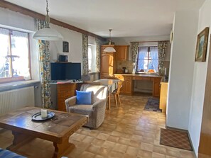 Ein gemütliches Zimmer mit einem Holztisch, einem bequemen Sessel und einem Fernseher.