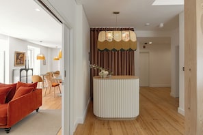 Interior moderno com ilha central, piso de madeira e área de estar com sofá vermelho.