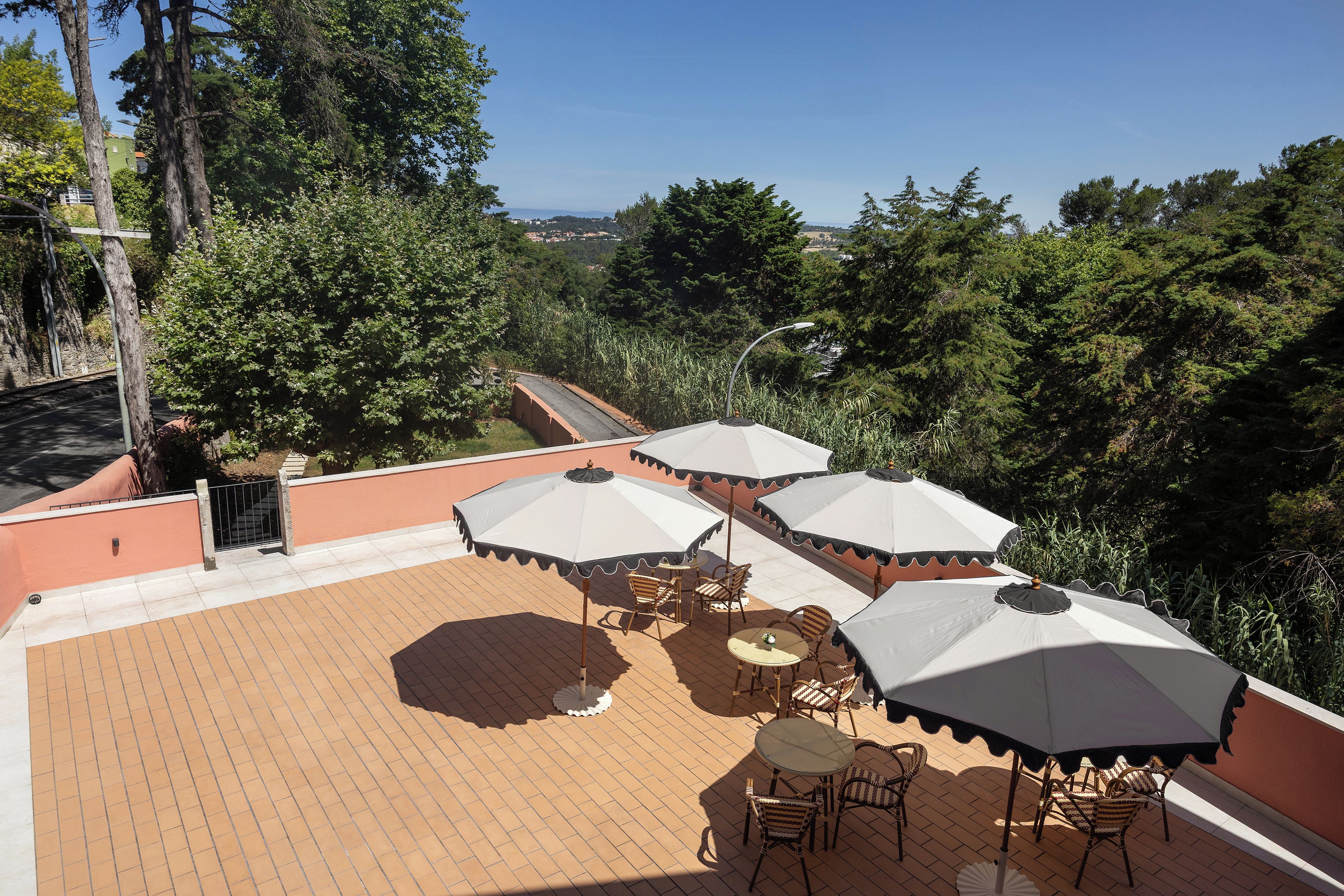 Une terrasse sur le toit, dotée d’un espace extérieur aménagé avec des sièges, des parasols et offrant une vue sur la verdure environnante.