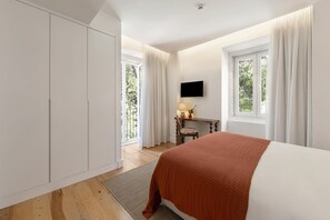 Un dormitorio con cama, escritorio con lámpara, televisor y armario.