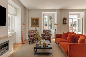 Una sala de estar con chimenea, dos sillones, un sofá, una mesa de centro y un cuadro en la pared.