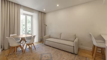 Un salon moderne avec une table à manger ronde, deux canapés et un tapis à motifs.