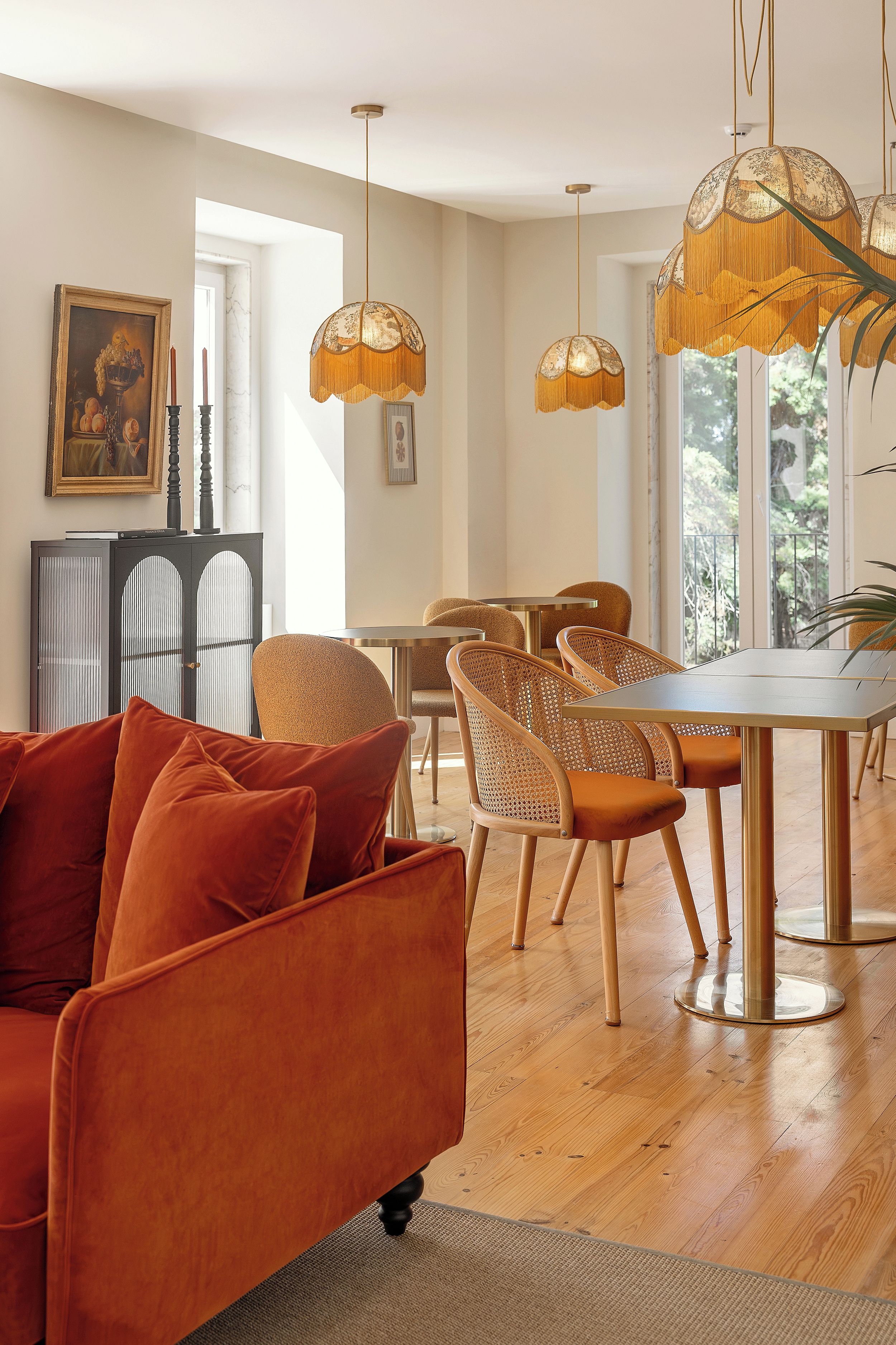 A modern living room with a sofa, dining table, chairs, and pendant lights.