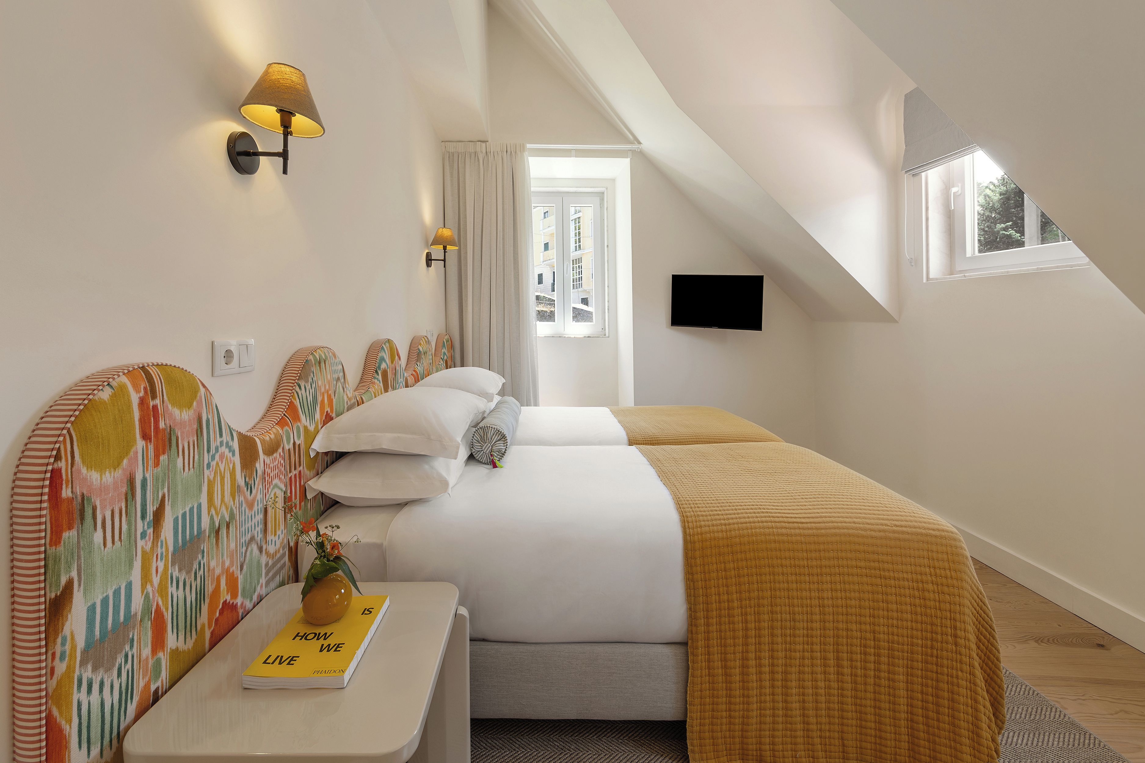 A modern bedroom with a bed, a bedside table, a lamp, and a TV.