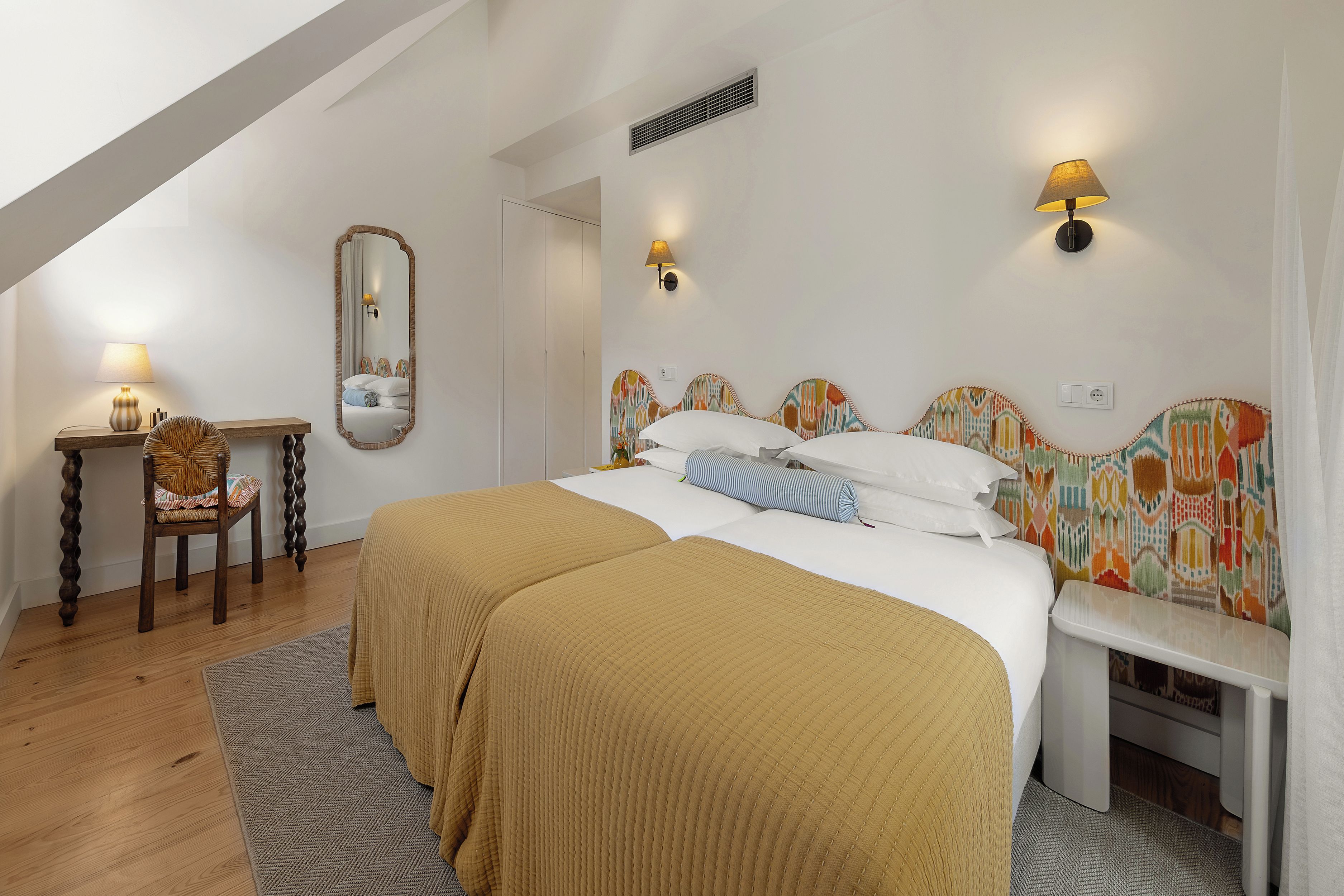 A bedroom with a large bed, a bedside table, a chair, and a mirror.