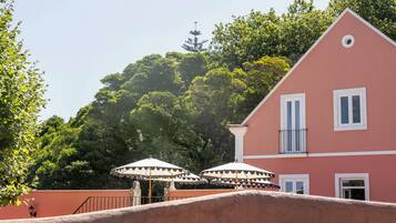 Un bâtiment rose avec des encadrements de fenêtres blancs et un balcon agrémenté de parasols.