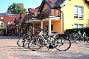 A row of bicycles parked in front of a yellow building with a balcony. - Comfort "Am Spreewaldfliess" (Schlepzig)