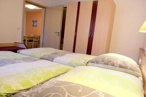 A hotel room with two beds, a wooden wardrobe, a dining table, and a chair. - Comfort "Am Spreewaldfliess" (Schlepzig)