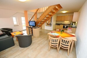 A modern living space with a dining area, a kitchen, and a staircase. - Comfort "Am Spreewaldfliess" (Schlepzig)