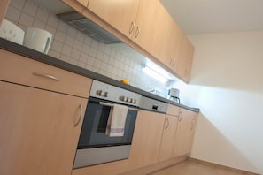 A kitchen with wooden cabinets, a stainless steel oven, and a coffee maker on the countertop. - Comfort "Am Spreewaldfliess" (Schlepzig)