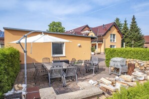 An outdoor patio area with a table and chairs, a barbecue grill, and a covered seating area. - Comfort "Am Spreewaldfliess" (Schlepzig)