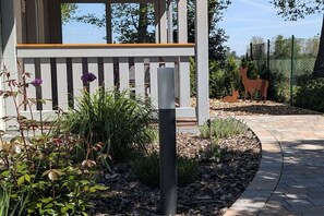 Ein Gartenbereich mit einer Pergola, einem Metallpfosten und einer Hirschskulptur.