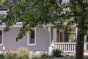 A residential house with a porch, a tree in the foreground, and a garden with various plants and flowers. - Country house holiday apartment Lüßvitz (Ummanz)
