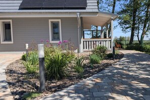 A modern house with a covered porch, solar panels, and a landscaped garden with various plants and flowers. - Country house holiday apartment Lüßvitz (Ummanz)