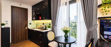 A modern kitchen with dark cabinetry, a round dining table with two chairs, and a large window with curtains.