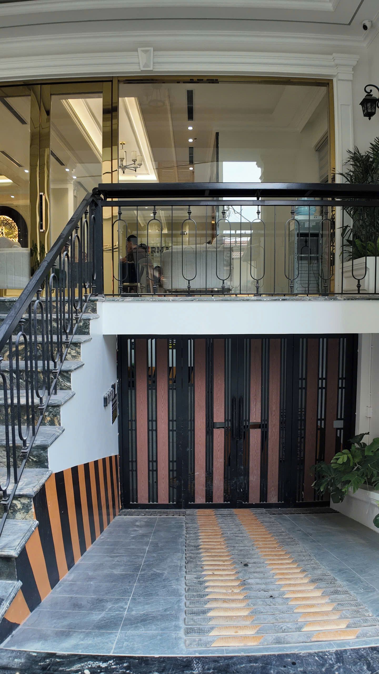 Ingresso di un hotel con porta in vetro, una scala e una rampa dotata di pavimentazione tattile.