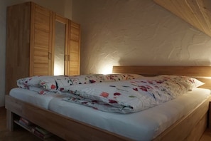 Ein Schlafzimmer mit einem hölzernen Bett, einem Kleiderschrank und einer Wand mit Struktur.