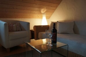 Ein gemütliches Zimmer mit einem Glastisch, zwei Weingläsern und einer Weinflasche.