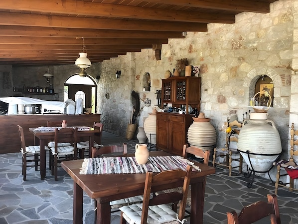 Un área de comedor al aire libre con suelo de piedra, mesas y sillas de madera.