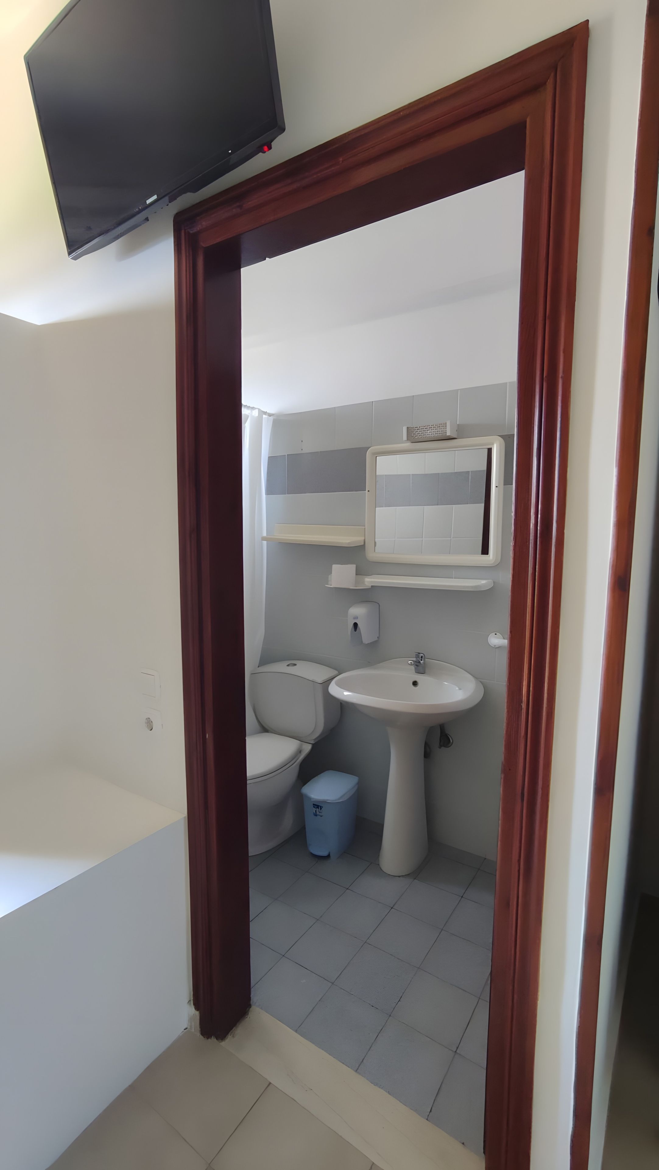 Une salle de bain avec des toilettes, un lavabo et un miroir au-dessus du lavabo.