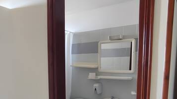 Une salle de bain avec des toilettes, un lavabo et un miroir au-dessus du lavabo.
