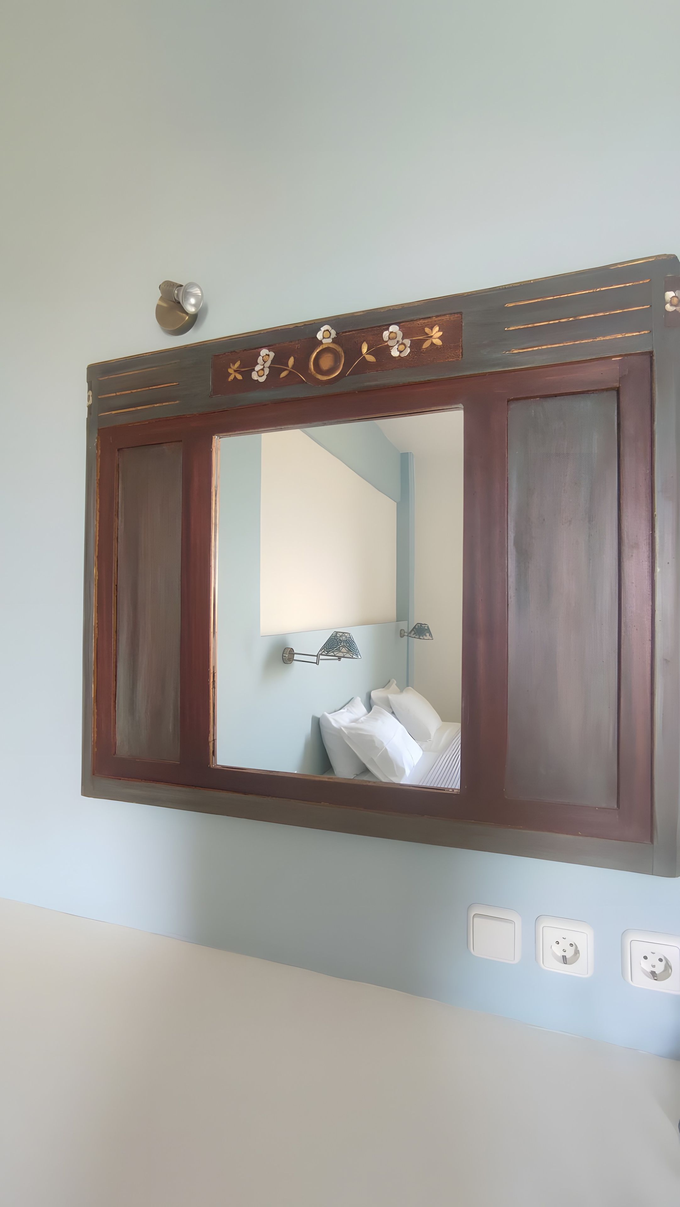 Une salle de bain avec un grand miroir, un porte-serviettes et un interrupteur.