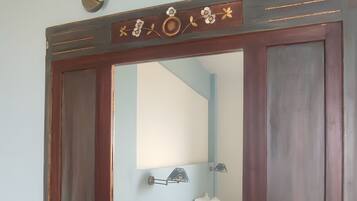 Une salle de bain avec un grand miroir, un porte-serviettes et un interrupteur.