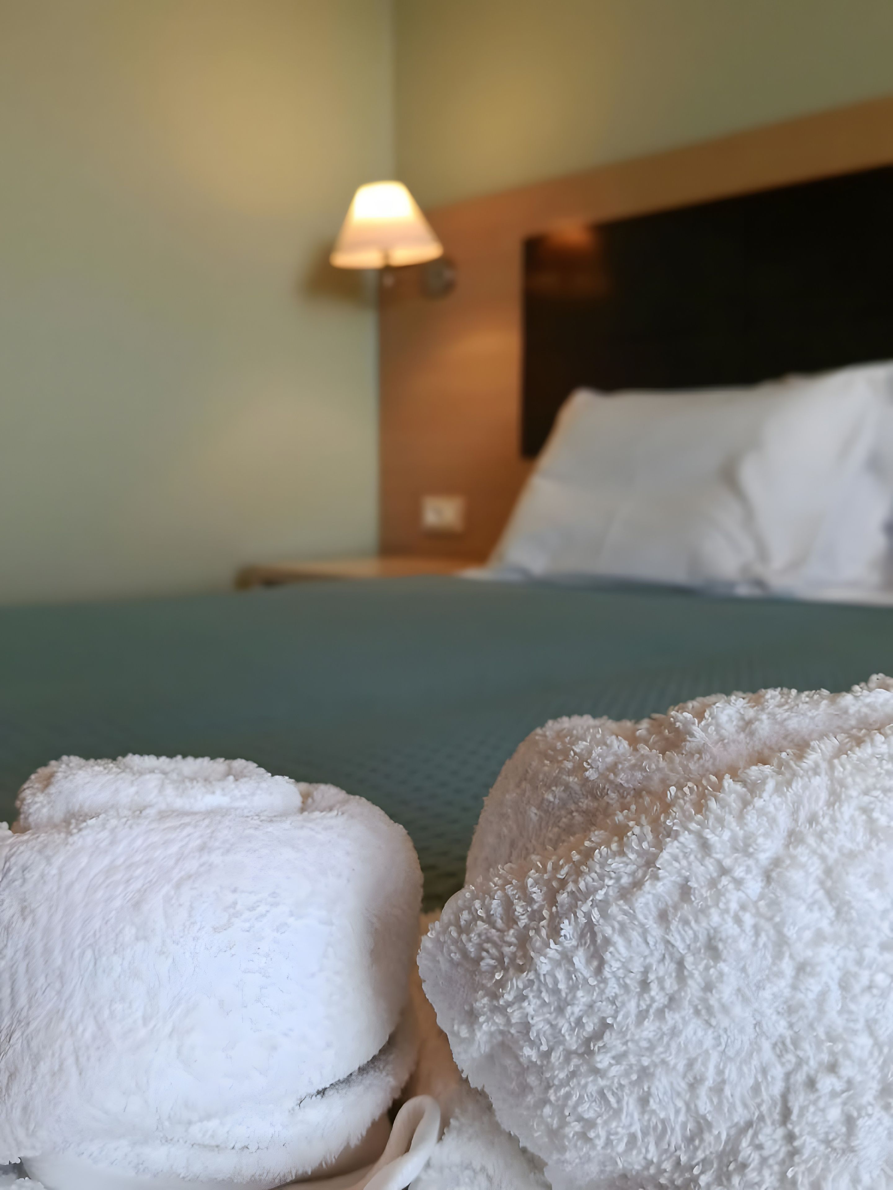 Ein Bett mit weißen Kissen und einer Lampe an der Wand.