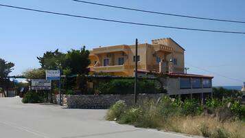 A two-story building with a flat roof and a stone wall in front.