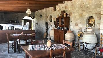 Un espace extérieur aménagé pour les repas, avec un sol en pierre, des tables et des chaises en bois.