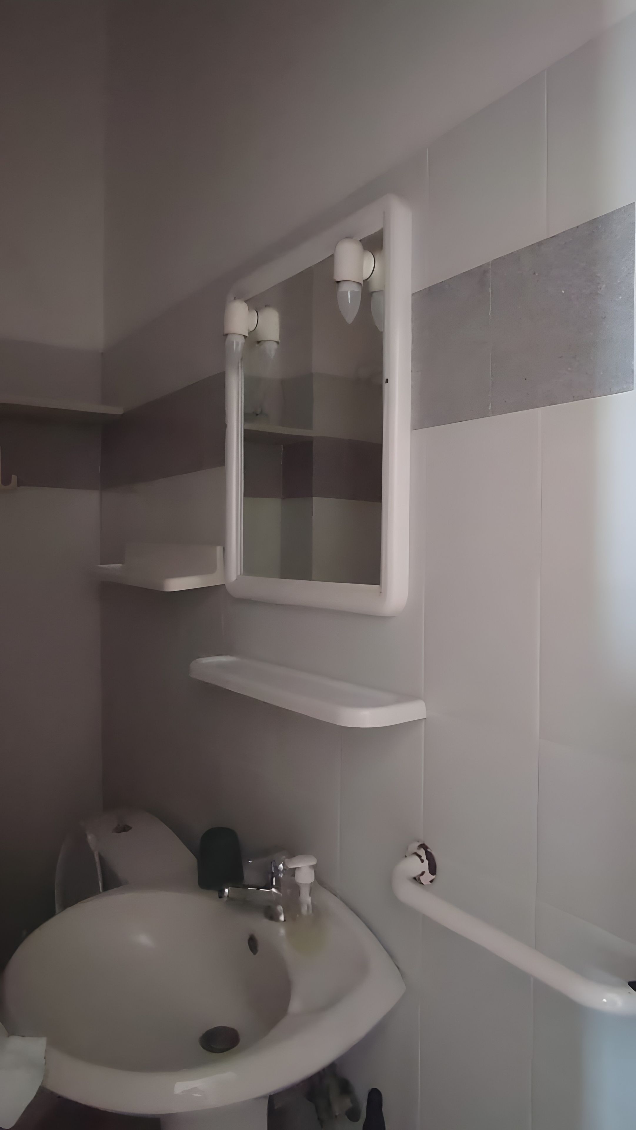 Un baño con un lavabo blanco, un espejo y un perchero para toallas.