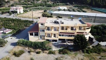 Un immeuble résidentiel à plusieurs étages, doté d’un toit plat, d’un balcon au deuxième étage et d’un petit jardin à l’avant.